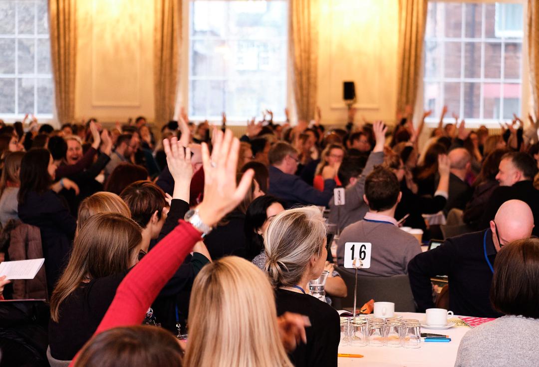 Delegates at a conference with their hands up