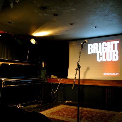 Bright club on projector screen behind microphone and piano