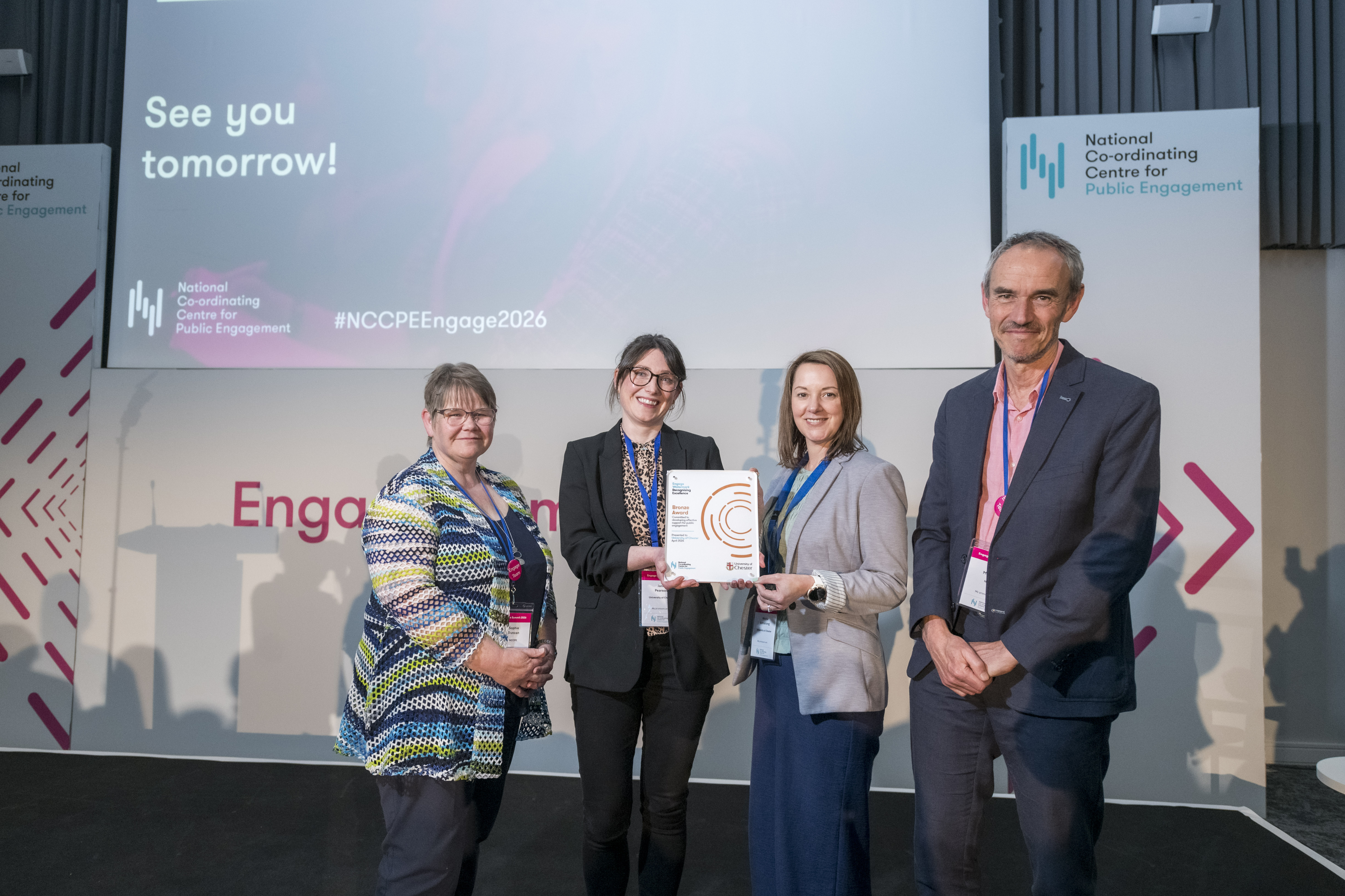 Four people standing on stage at Engage 2026 the two in the centre are holding an award