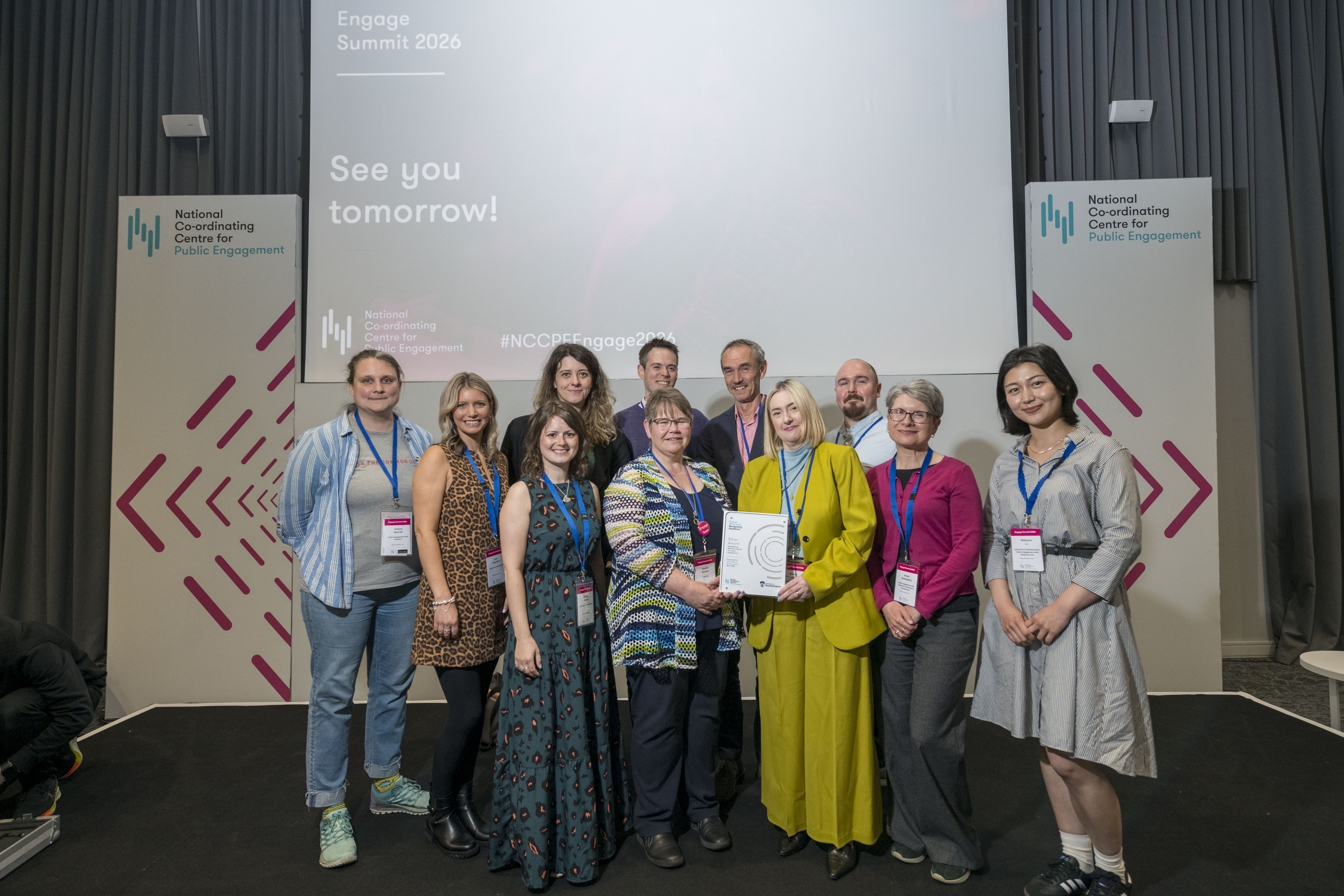 group of men and women holding award on stage and smiling