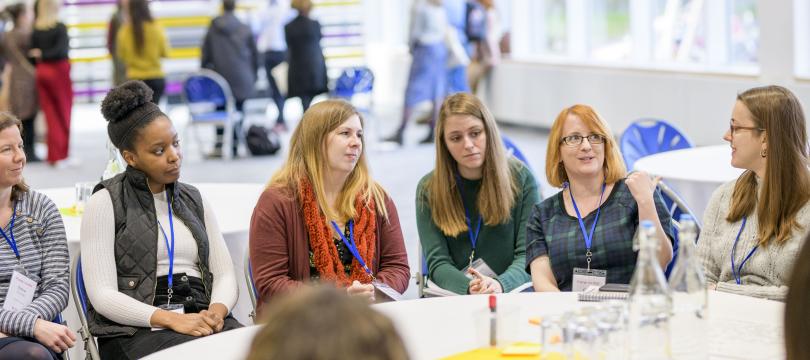 people sitting round a table talking to each other with other roundtable discussion group sin the background