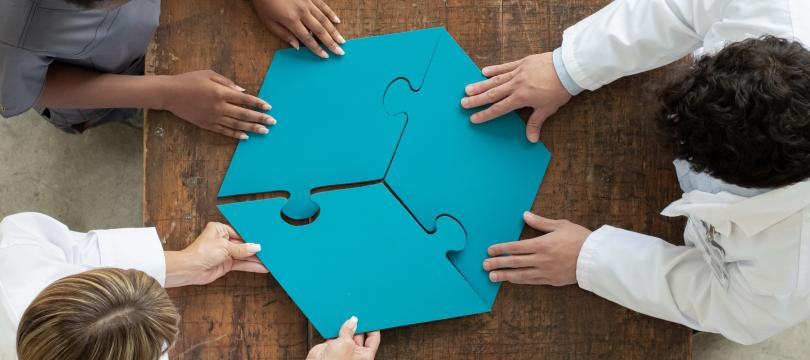 An arial view of 3 people putting together a jigsaw