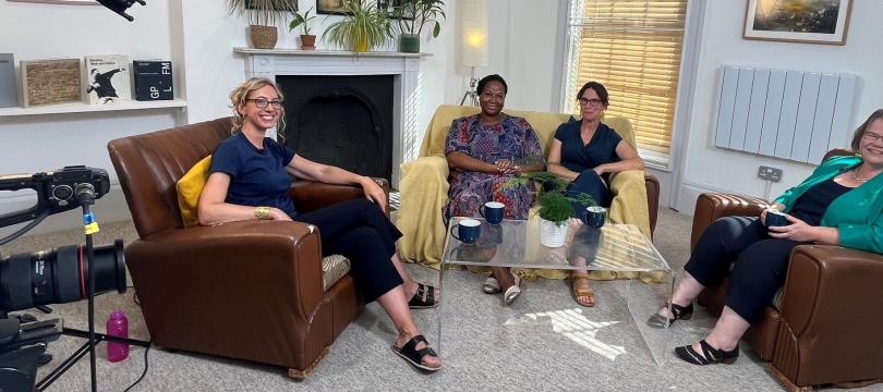 Sophie Duncan, Jude Fransman, Fay Scott, Louise Archer (R-L) sat in armchairs around a coffee table, with filming and sound equipment around them, smiling at the camera
