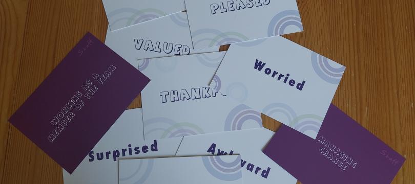 A collection of cards with words that describe feelings for example powerless, encouraged, pleased.