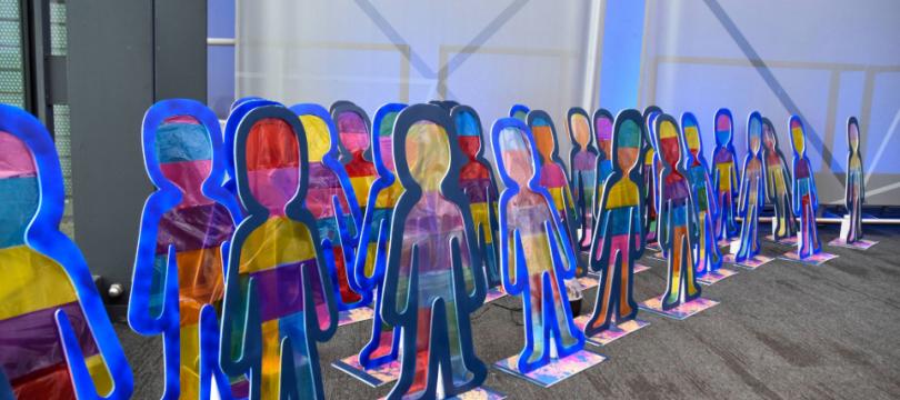  A photo of artwork made by children, lots of cut out colourful people