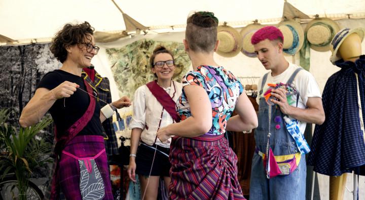 group of 4 people in bright clothes engaging at a festival