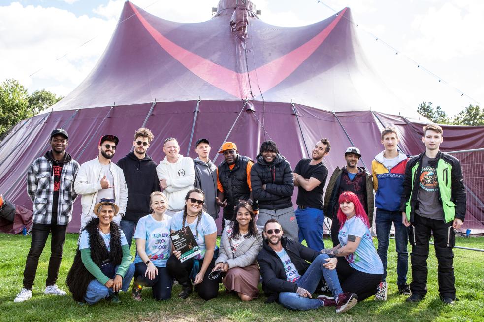 group of young people working with Derby University standing and sitting outside in front of a big purple tent