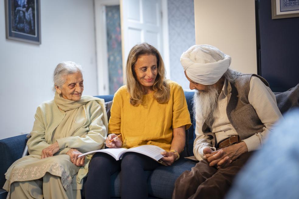 an older man and woman smiling and speaking with a younger woman