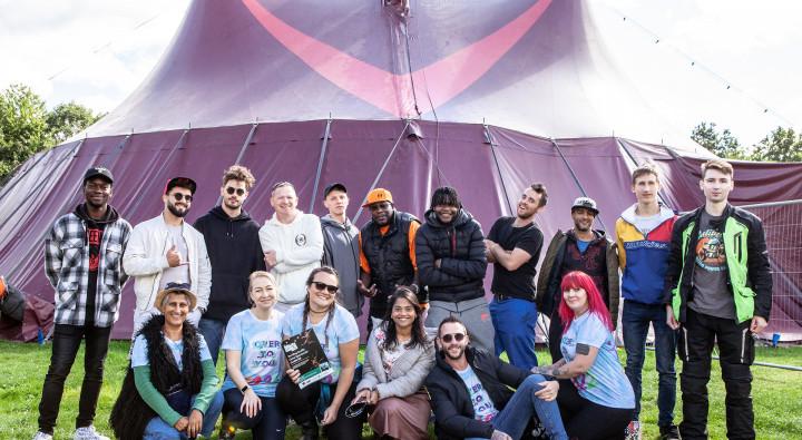 Diverse group of people smiling in front of festival tent