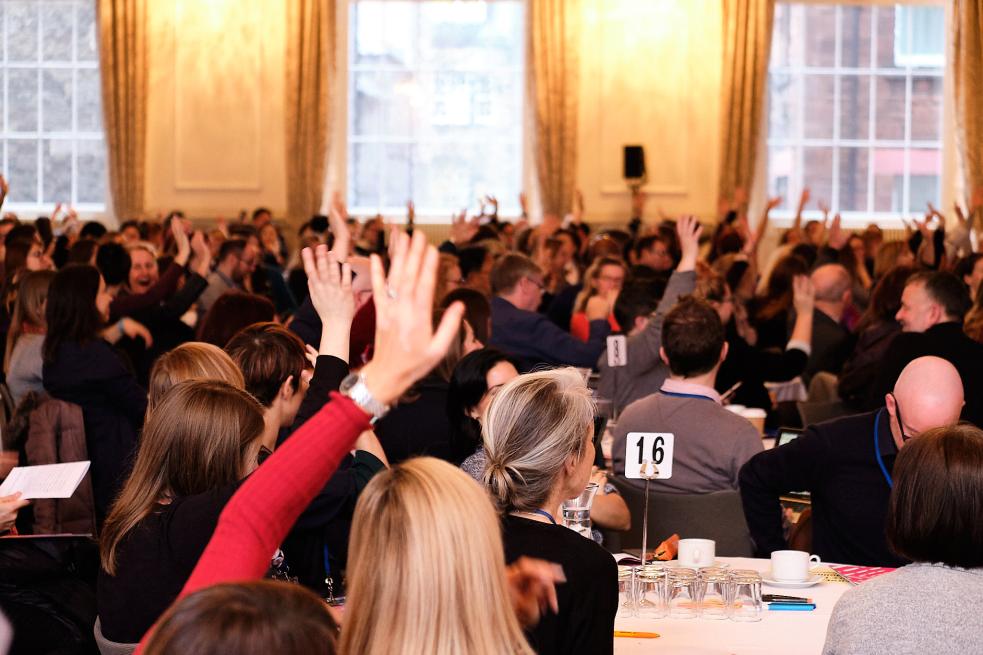 Delegates at a conference with their hands up