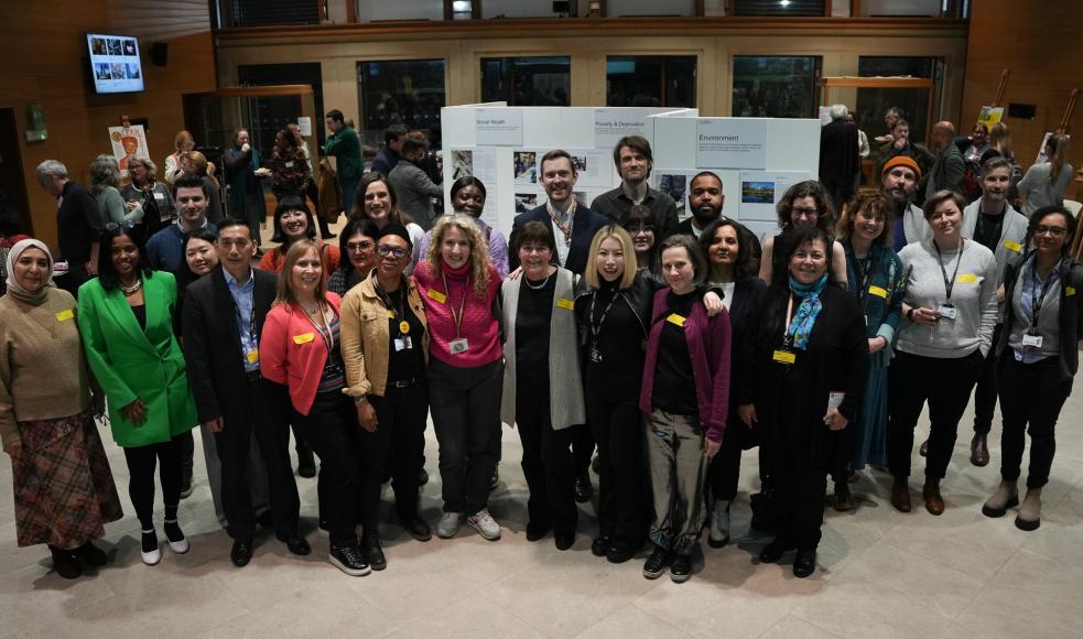 A group shot of the LMU team and community members at an event, with everyone stood facing the camera and smiling 