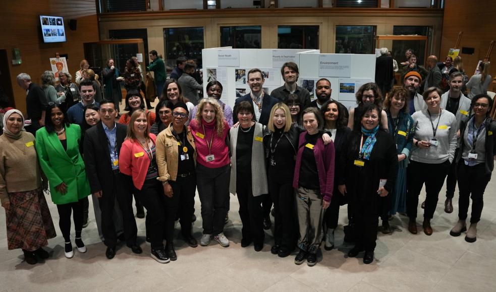 A group shot of the LMU team and community members at an event, with everyone stood facing the camera and smiling