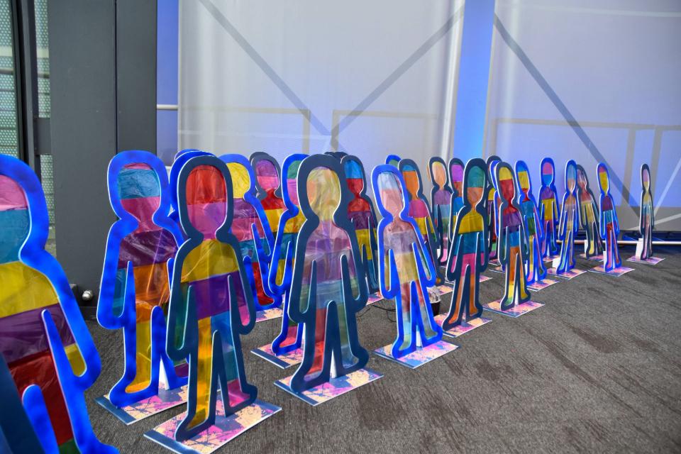  A photo of artwork made by children, lots of cut out colourful people