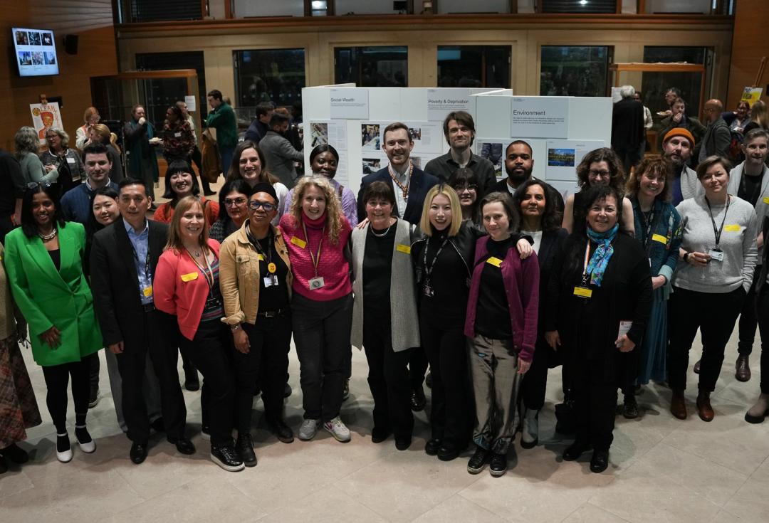 A group shot of the LMU team and community members at an event, with everyone stood facing the camera and smiling 