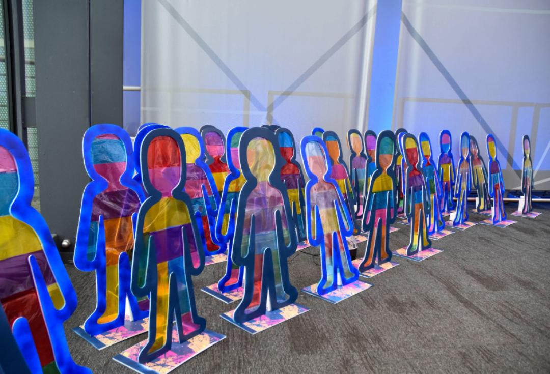  A photo of artwork made by children, lots of cut out colourful people