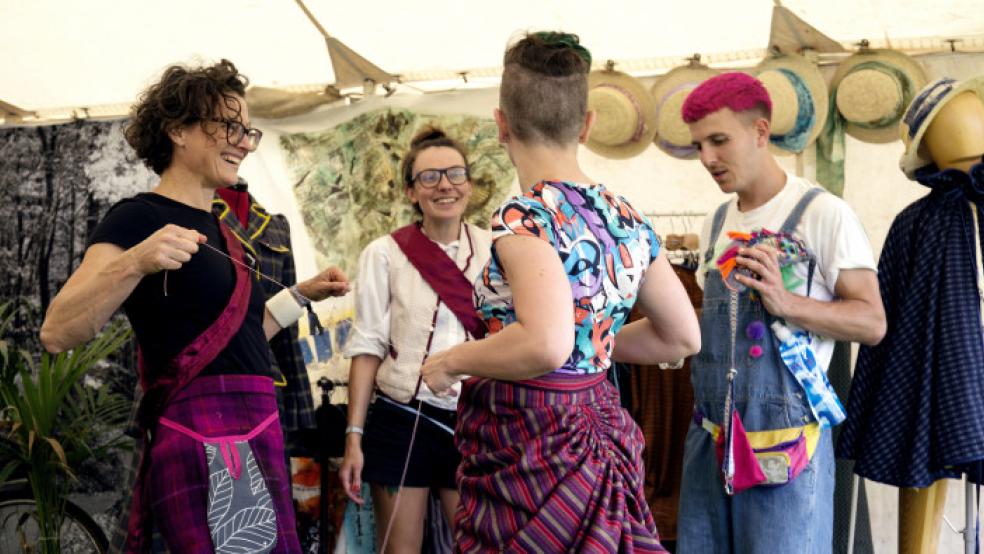 group of 4 people in bright clothes engaging at a festival