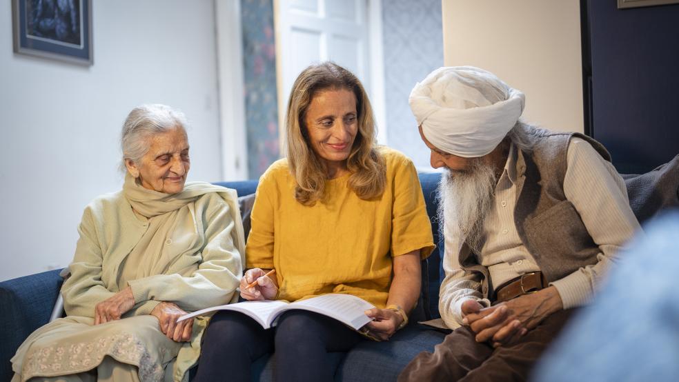 an older man and woman smiling and speaking with a younger woman