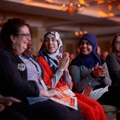 women clapping and celebrating together in event audience