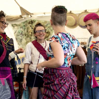 group of 4 people in bright clothes engaging at a festival