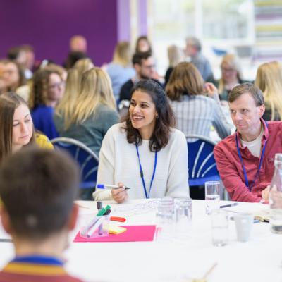 group talking and laughing at roundtable at Engage Live 2022 with many other groups in the background