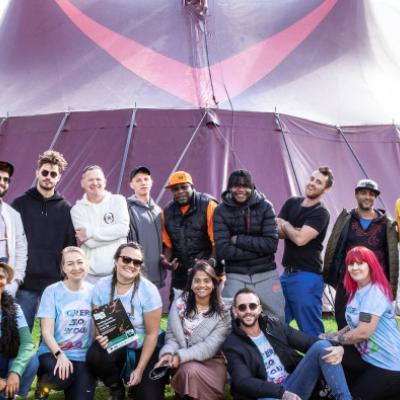 Diverse group of people smiling in front of festival tent