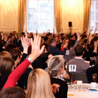 Delegates at a conference with their hands up