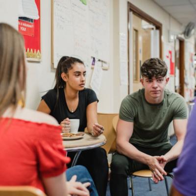 Group of 3 young people and older person speaking together 