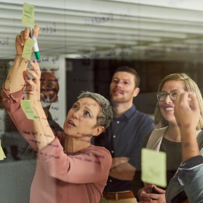 A group of 5 people using post-it notes on a wall to plan