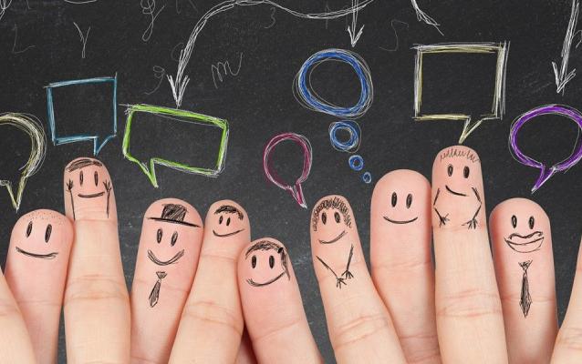 Lots of fingers with faces drawn on them and speech bubbles on a blackboard above them