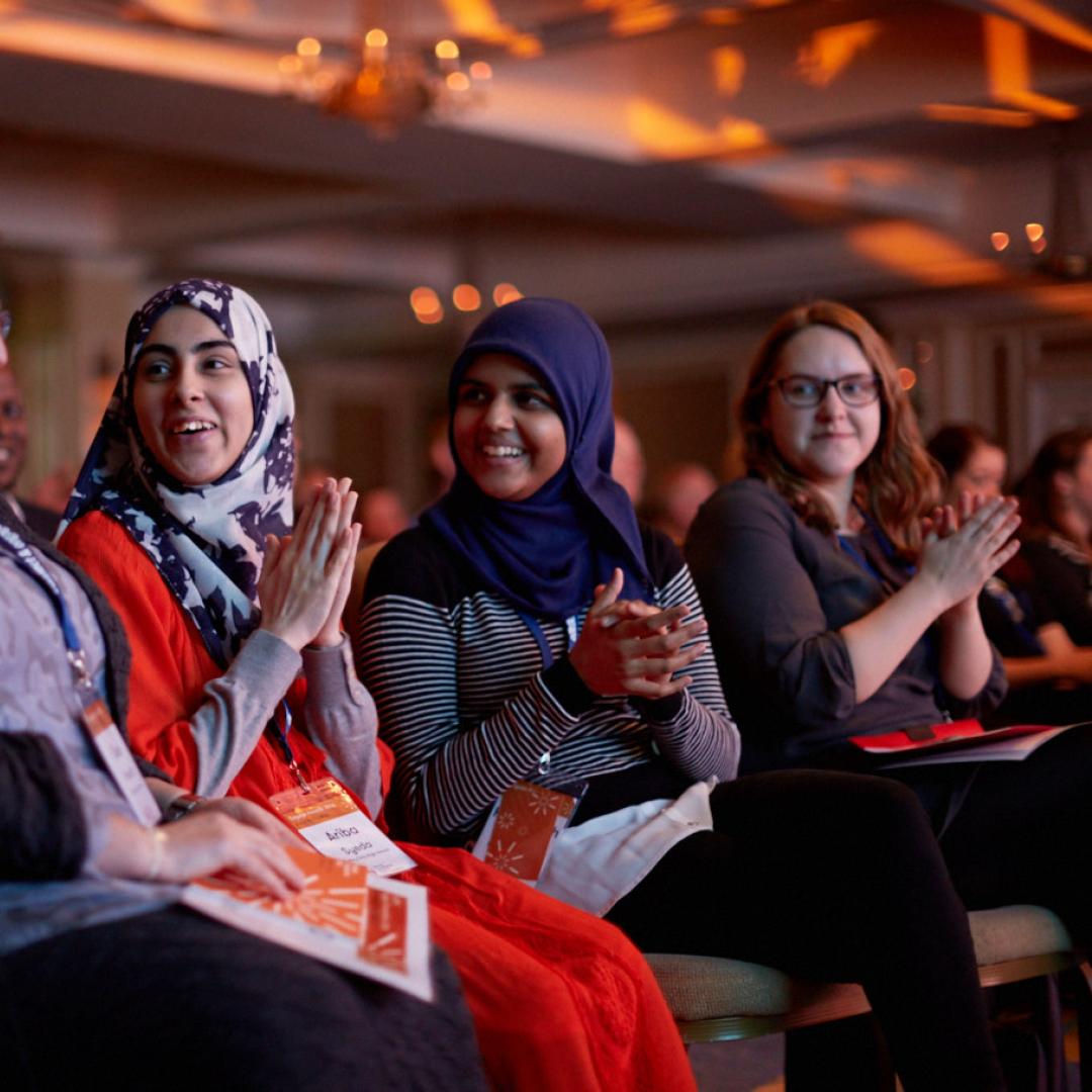 women clapping and celebrating together in event audience