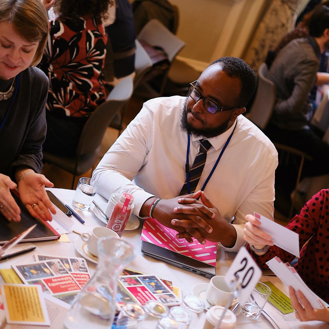 group of men and women talking around table with other round discussions happening in the background