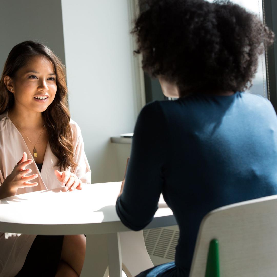 two women talking to each other across a table