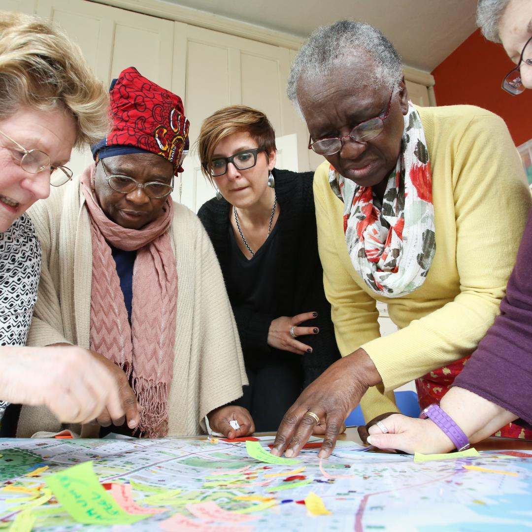 An image of a researcher and 4 co-researchers working on a project about age friendly cities